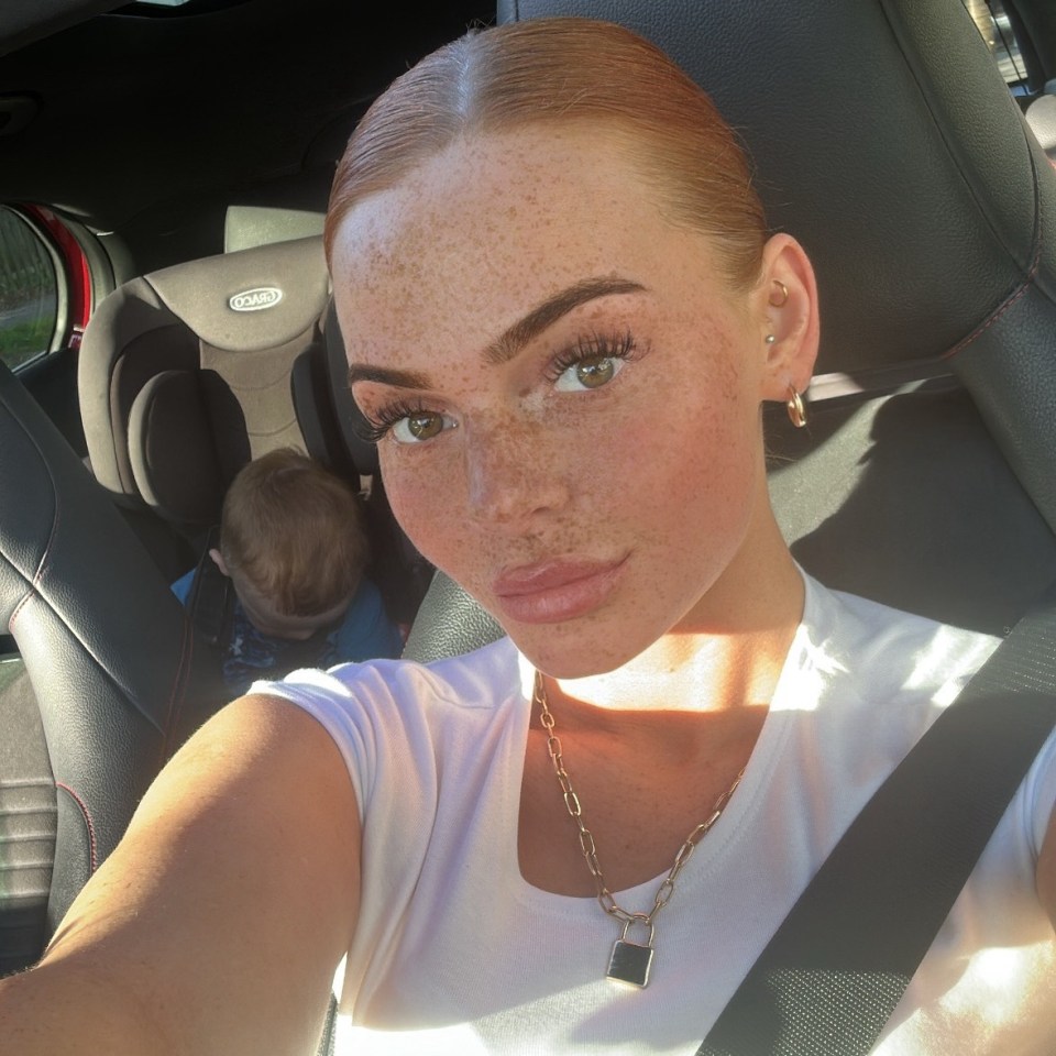 Woman with freckles and a toddler in the background.