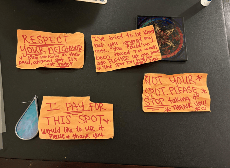 Handwritten notes left on a surface regarding a parking spot dispute.