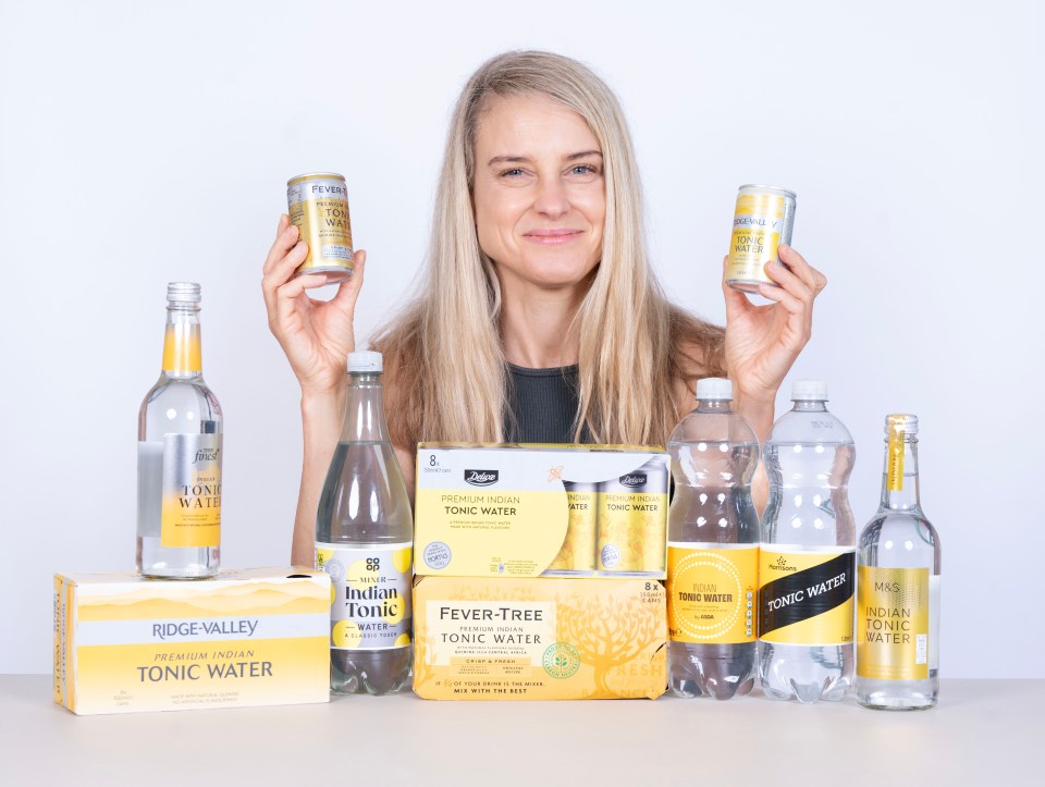 Woman holding various brands of tonic water.