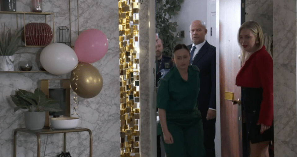 People standing in a doorway, balloons in the background.