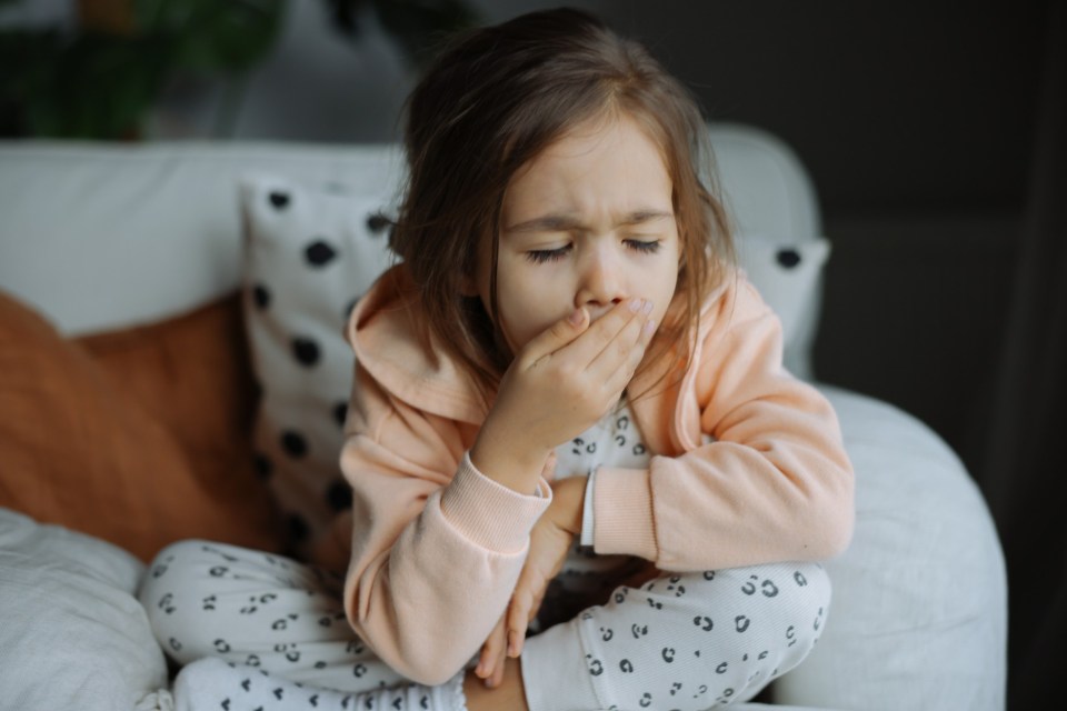 Poor, unfortunate little brunette preschooler child, girl in pajamas coughing, lying in soft bed. Sore throat, angina