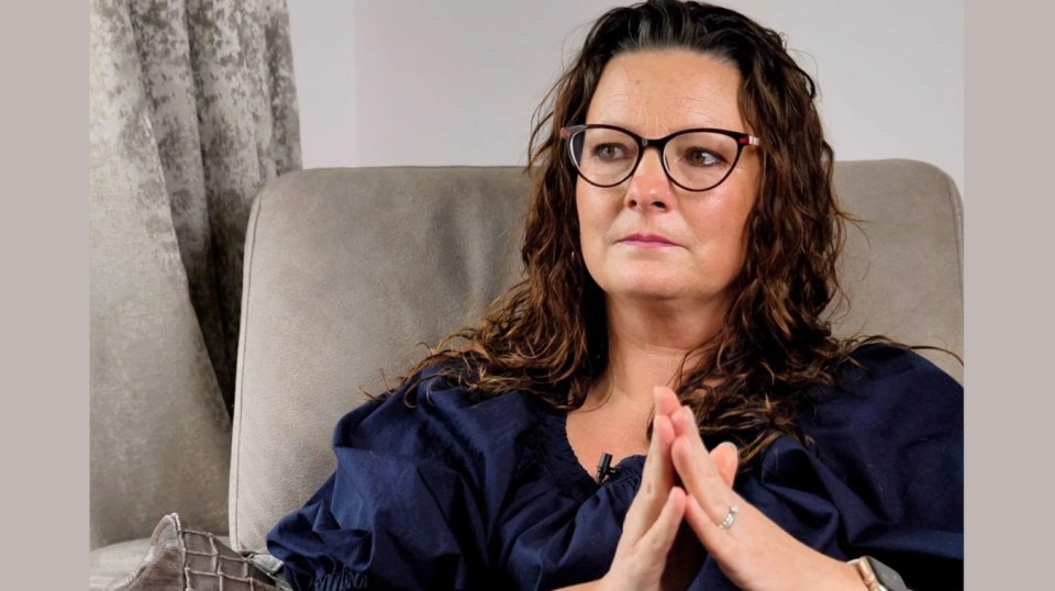 Woman with glasses sitting in a chair.