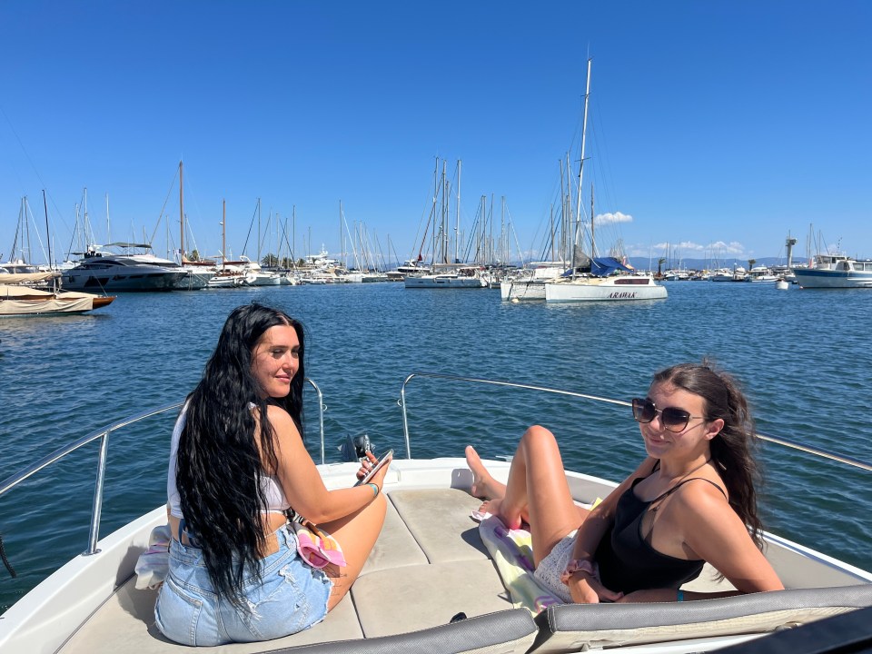Two women relaxing on a boat in a marina.