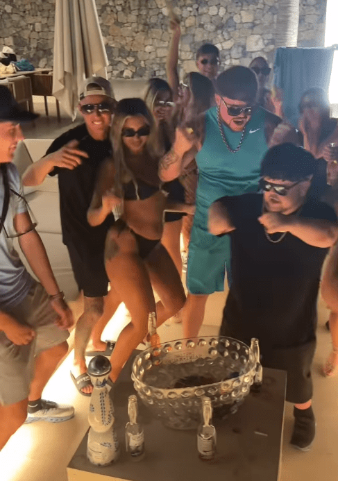 Group of people dancing around a drink cooler.