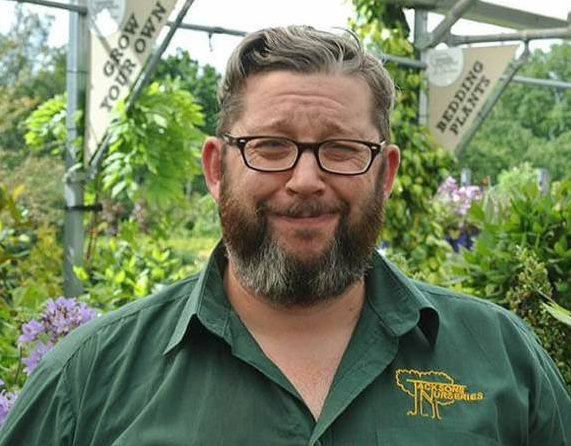 Man in green shirt at a plant nursery.