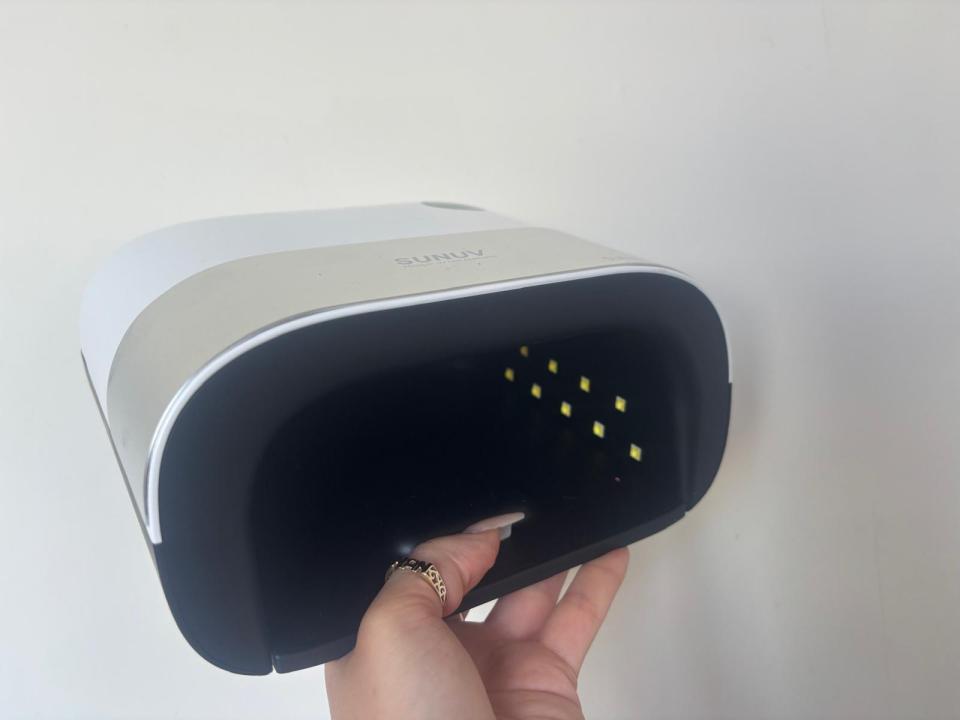 Hand holding open a SUNUV LED nail lamp.