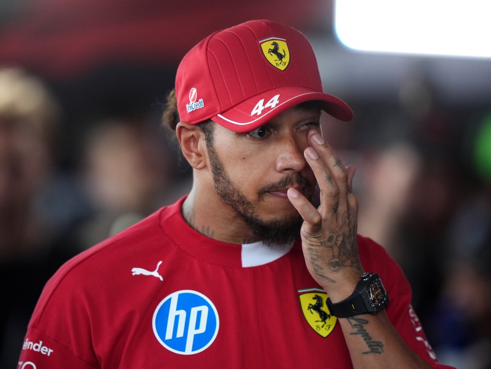 Lewis Hamilton in Ferrari attire wiping his eye.