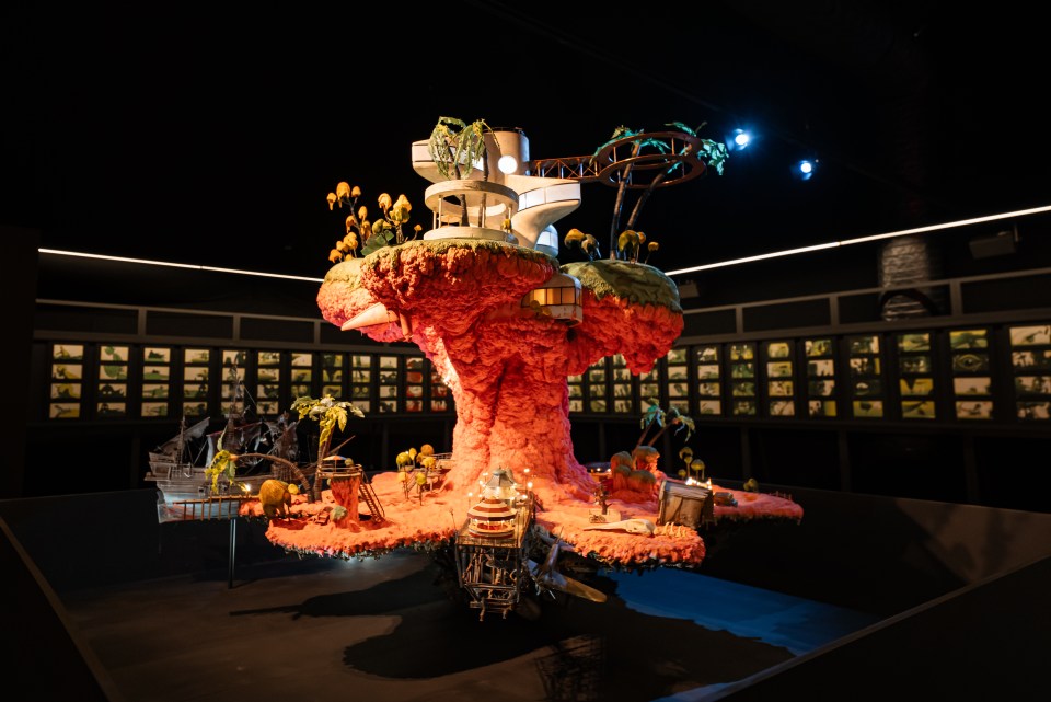 Model of a fantastical island with buildings and palm trees.