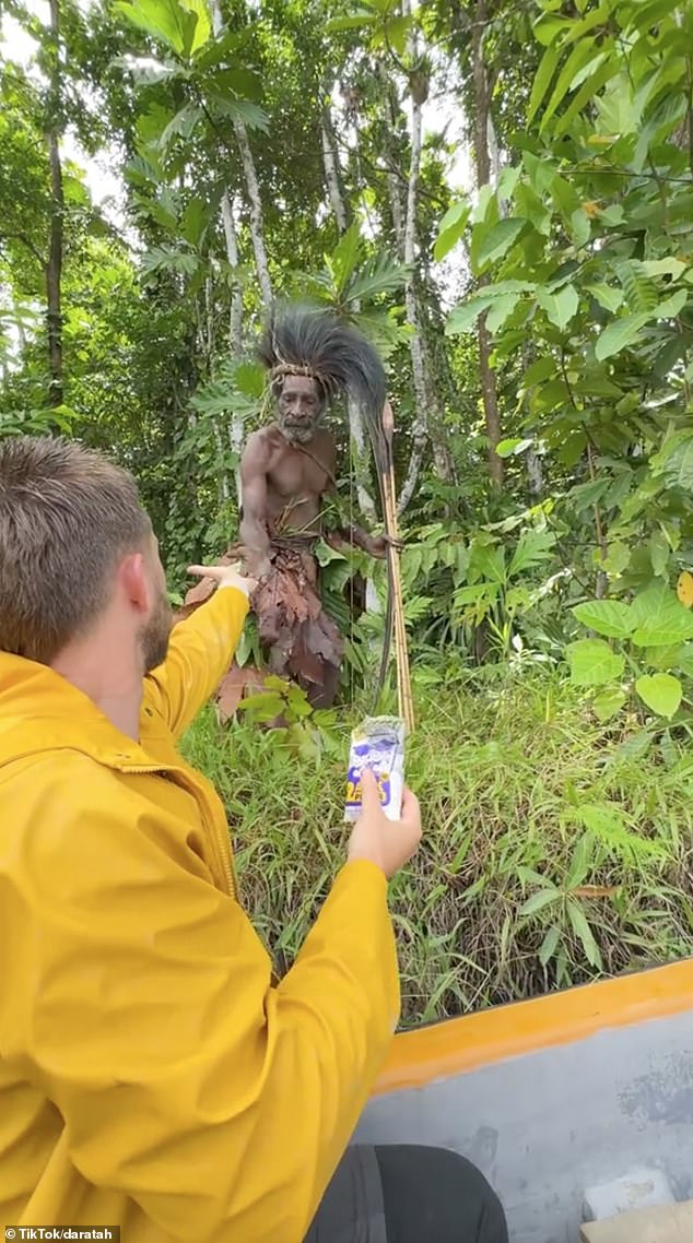 The footage shows tribesmen looking suspiciously at their visitors - with one even aiming an enormous bow and arrow towards their boat