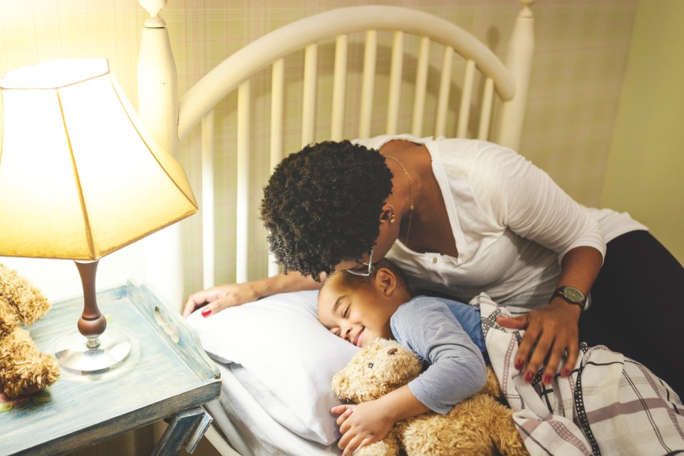 Mother kissing her son goodnight.