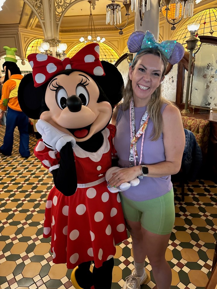 Woman in Minnie Mouse ears posing with Minnie Mouse.