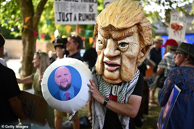 A protester holding a satirical photo of JD Vance at a 'Vance not welcome' party in Charlbury