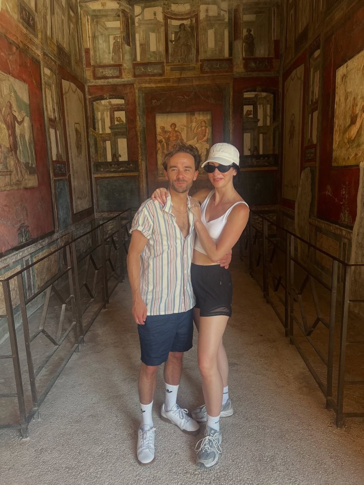 Couple posing in a room with ancient Roman frescoes.
