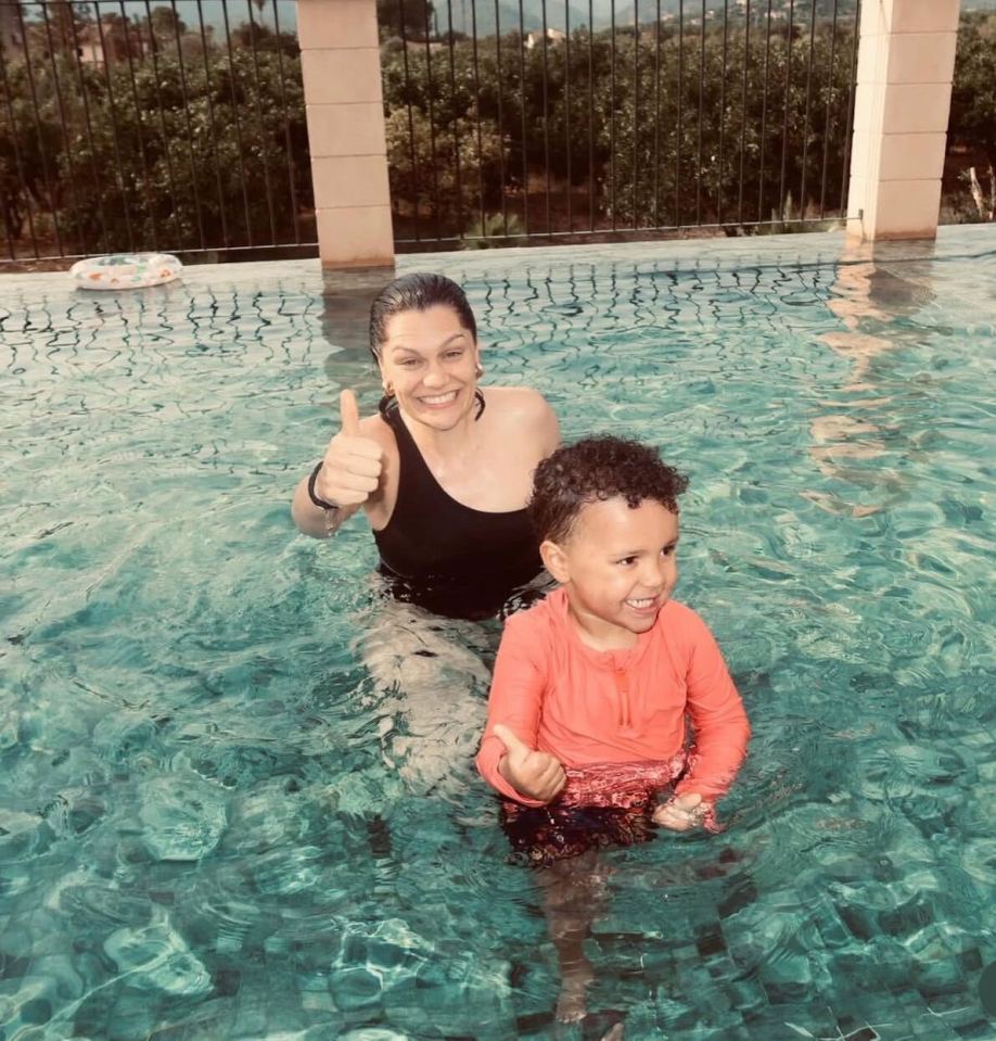 Woman and child giving thumbs up in a swimming pool.