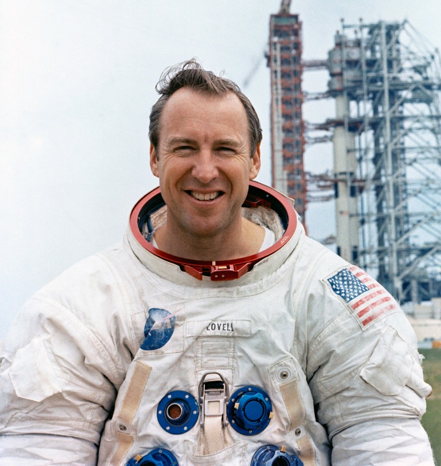 Portrait of Jim Lovell, Apollo 13 commander, in a spacesuit holding a moon globe.