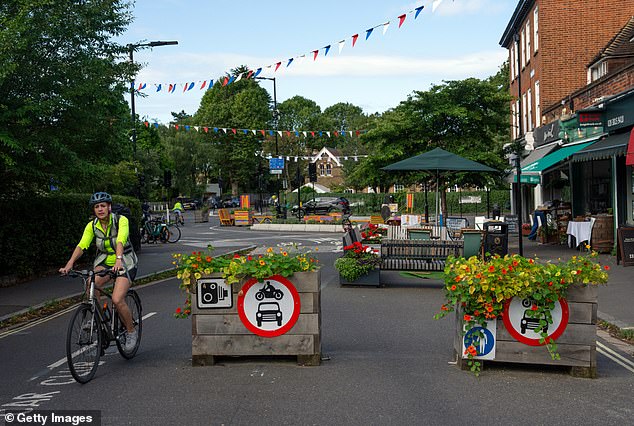 A cyclist passes planters blocking a road for cars in a Low Traffic Neighbourhood (LTN)