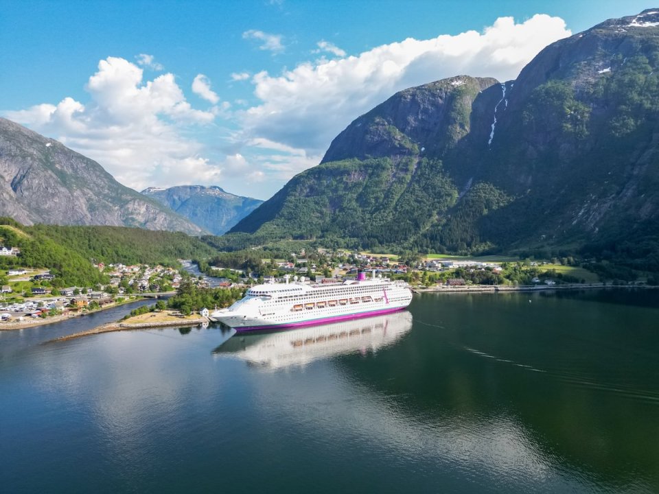 Cruise ship docked in a fjord surrounded by mountains.