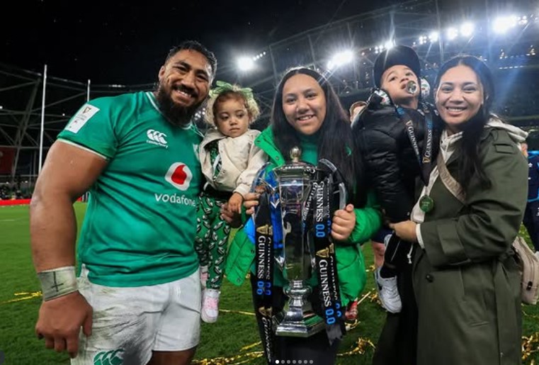 Bundee Aki and his family holding a rugby trophy.