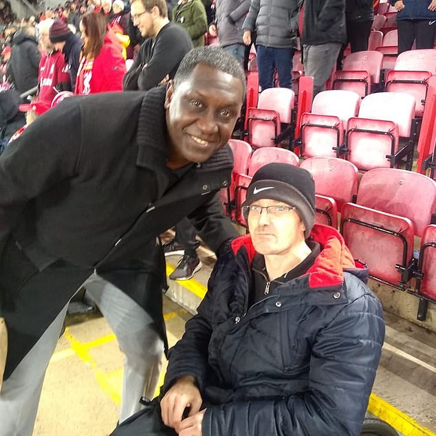 This is Mark Mogan, the disabled Liverpool fan, pictured right with Emile Heskey, who was arrested for allegedly shouting racist abuse at Bournemouth player Antoine Semenyo