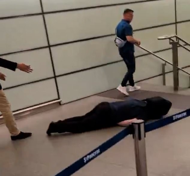 Tommy Robinson walks past a man who appears to have been knocked unconscious at St Pancras