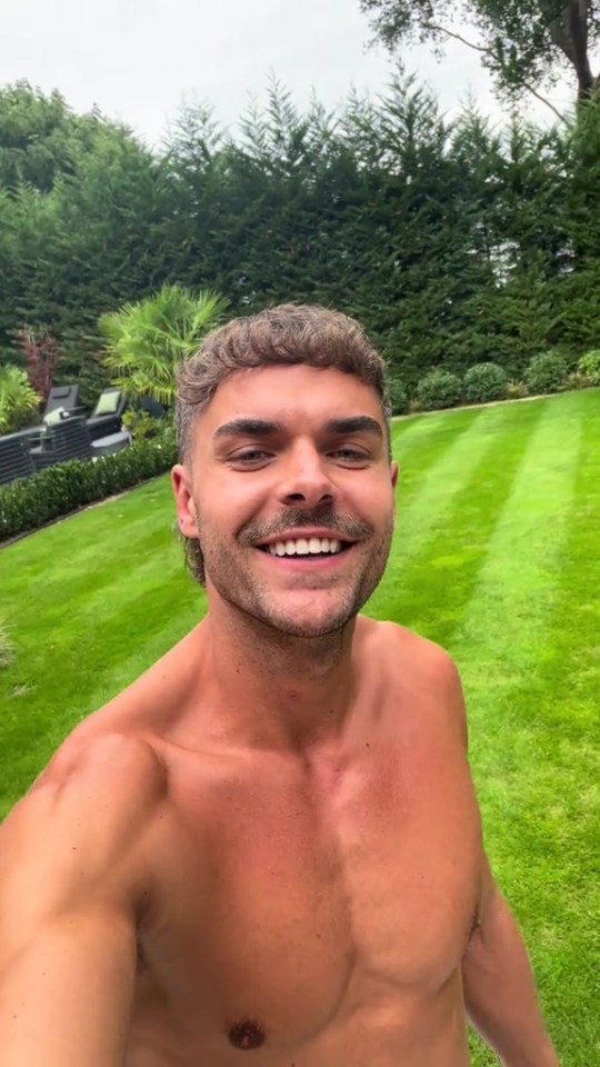 Shirtless man smiling in his large backyard.