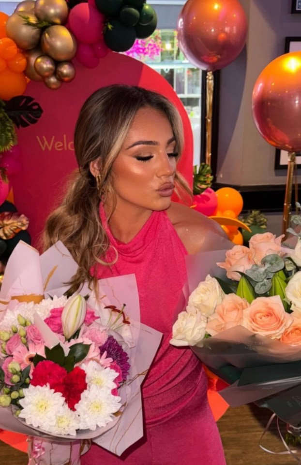 Woman in pink dress holding two bouquets of flowers.