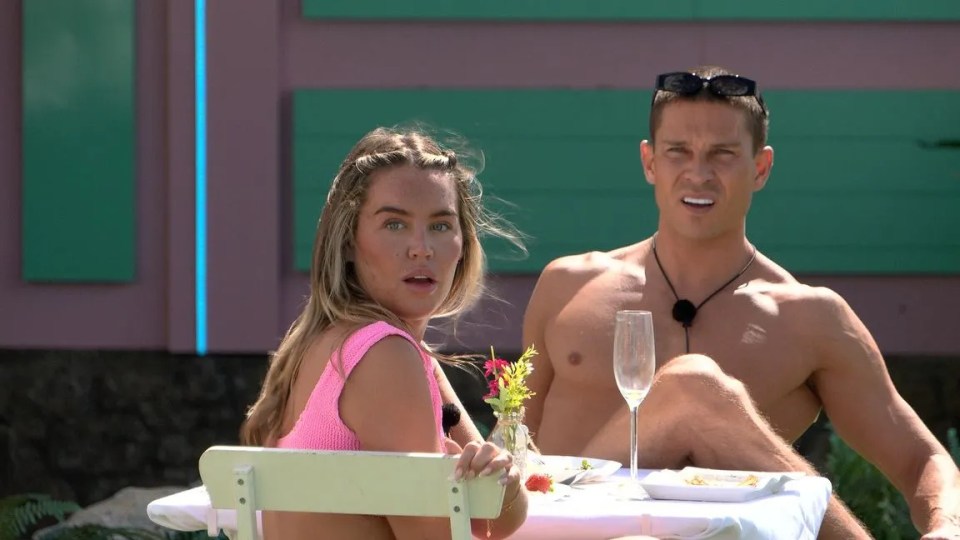 A man and woman sitting at a table outdoors.