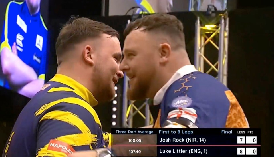 Josh Rock and Luke Littler facing each other during a darts match.  The scoreboard shows Rock winning 7-8.