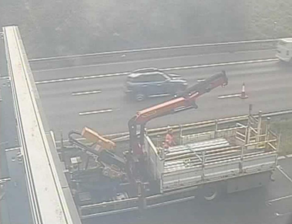 Truck with crane loading materials on a highway.