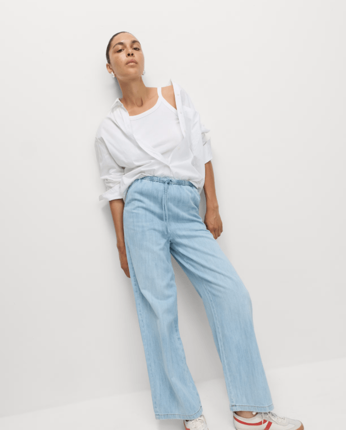 Woman modeling light wash drawstring trousers.