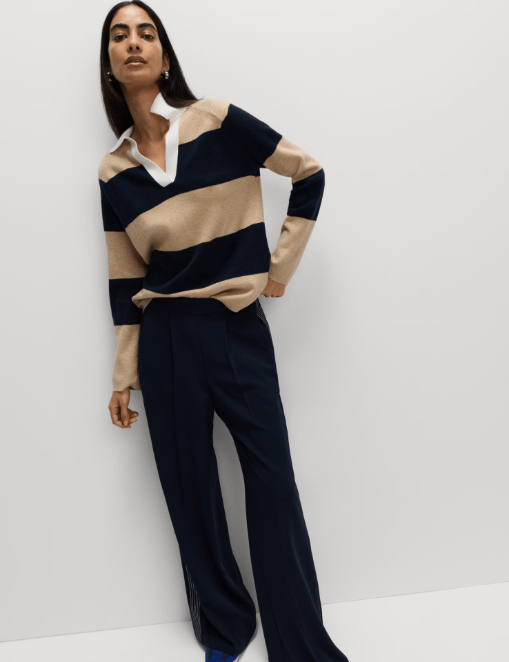 Woman wearing a striped sweater and dark pants.