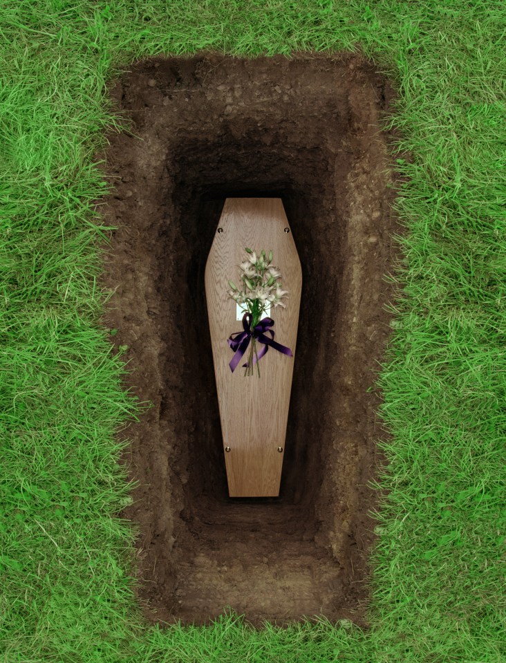 Overhead view of a coffin in a grave with flowers.