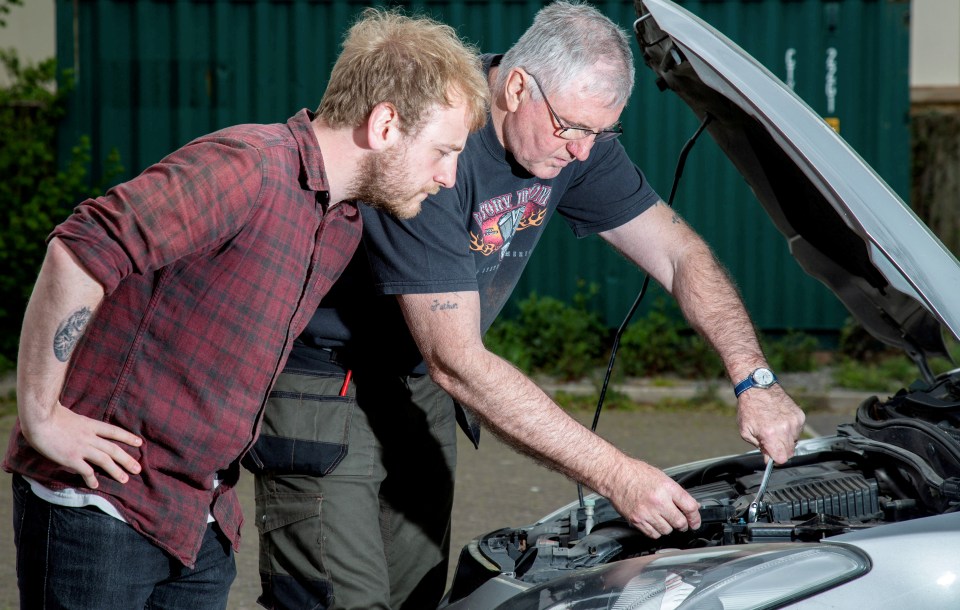 Two men working on a car engine.