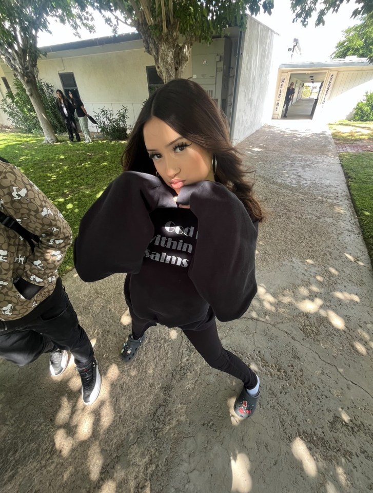 Teenager in black sweatshirt posing outdoors.