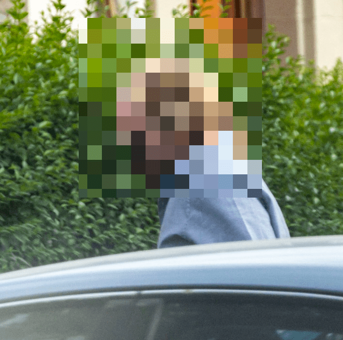Person's face obscured, leaning into a car.
