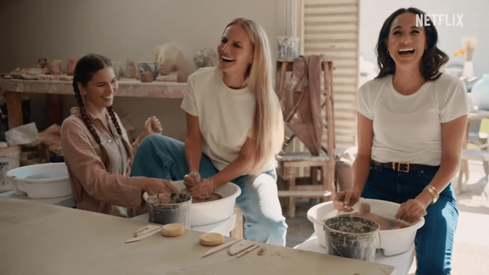 Three women laughing while participating in a pottery class.