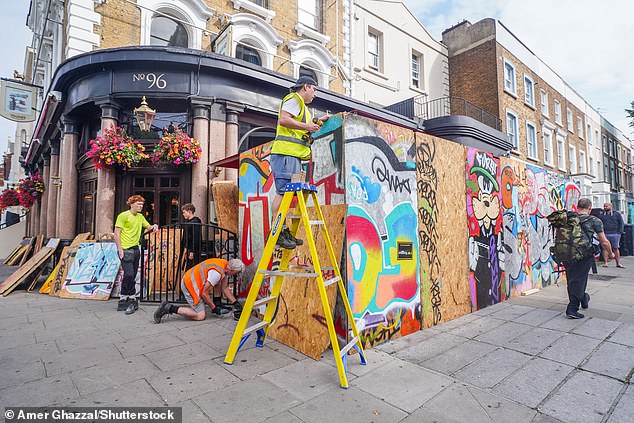 Workers board up the Elgin pub on Ladbroke Grove before the start of Notting Hill Carnival