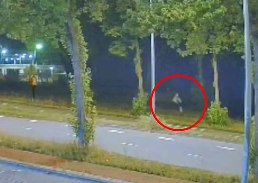 Nighttime security camera footage of a person running.
