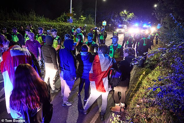 Protesters outside The Bell Hotel stand in front of a line of police officers on August 29