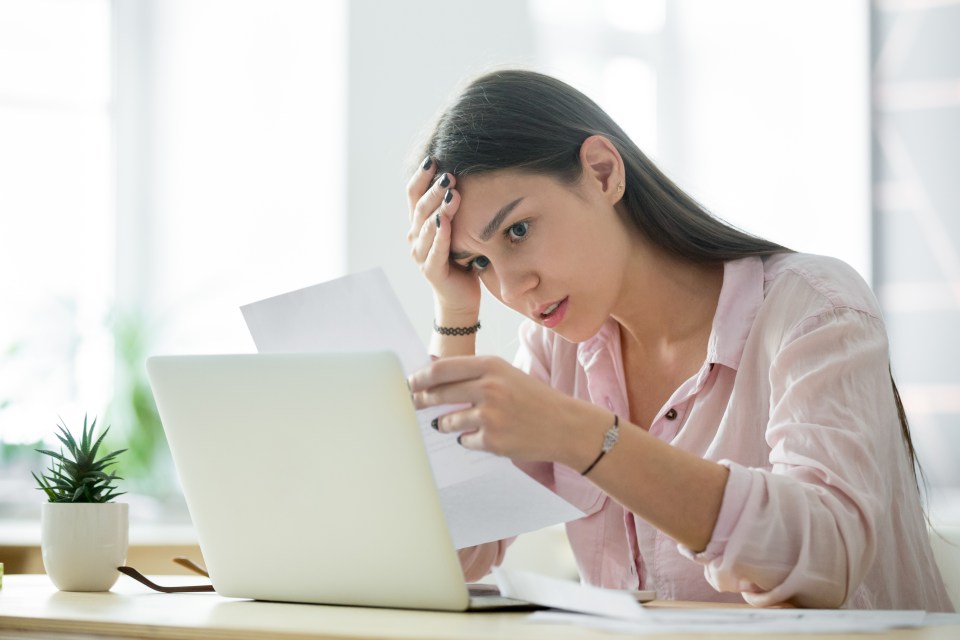 A stressed woman looks at upsetting paperwork.