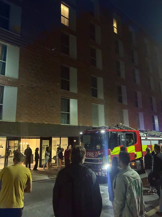Firetruck outside building at night with people gathered.