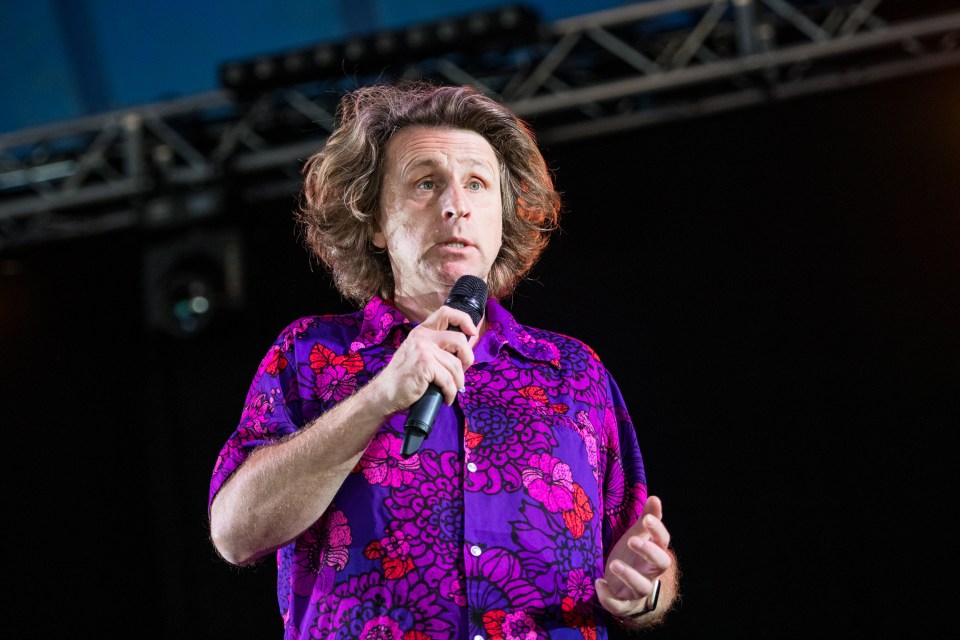 Comedian Milton Jones performing on stage.
