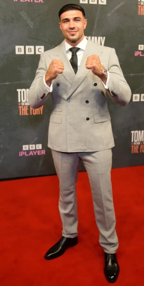 Man in gray suit on red carpet.