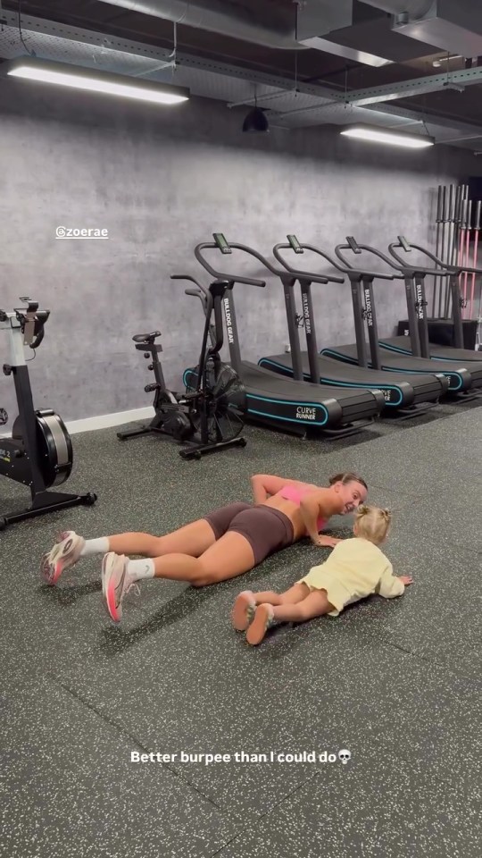 Woman and toddler doing burpees in a gym.