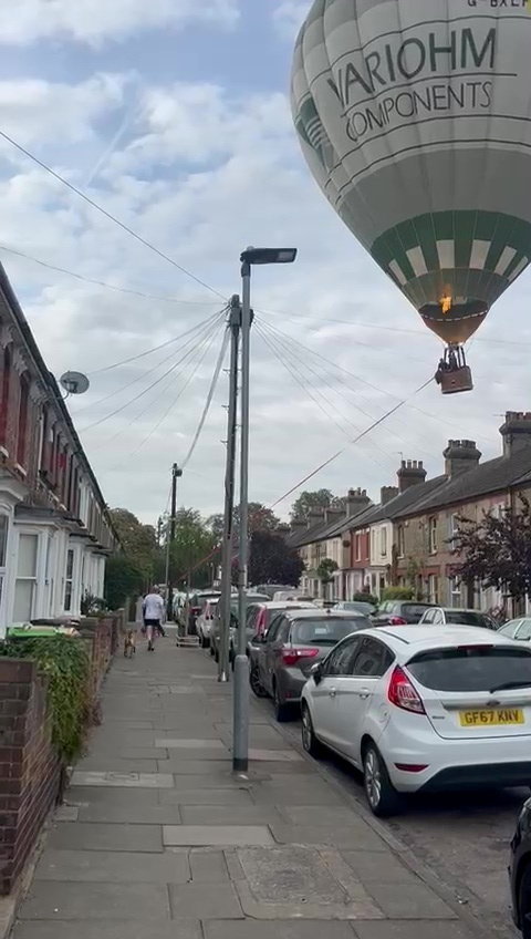Hot air balloon making an emergency landing in a residential street.