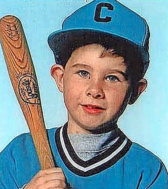Young boy in a baseball uniform holding a bat.