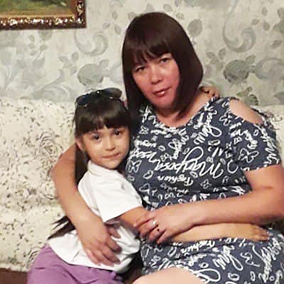 A mother and young daughter hugging on a couch.