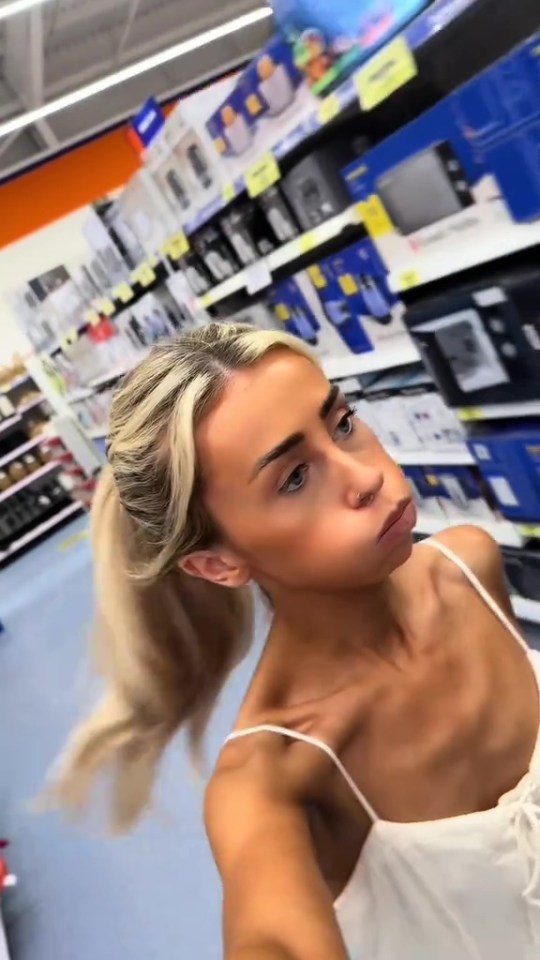 Woman in a store with shelves of appliances.
