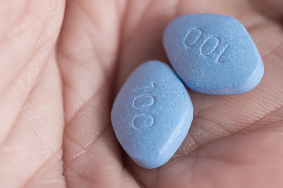 Two blue pills in a hand.