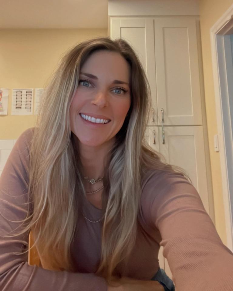 Woman with long blonde hair smiling at the camera.